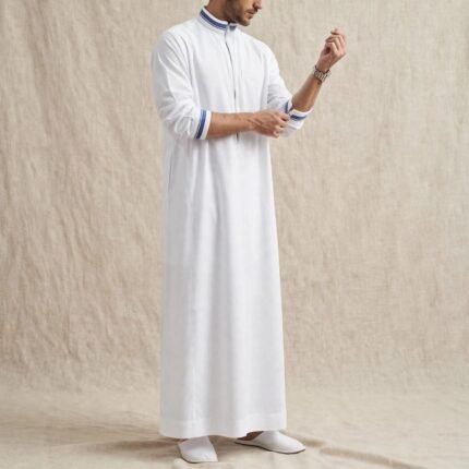 alt="White zipper thobe with blue contrast detailing on collar and sleeves - side pose - Emirati thobe for men"